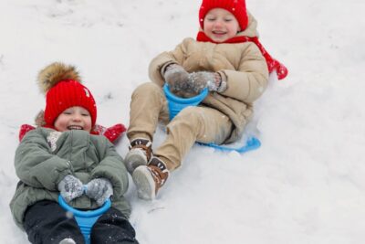 Joyful children sledding down a snowy hill, enjoying winter fun outdoors.