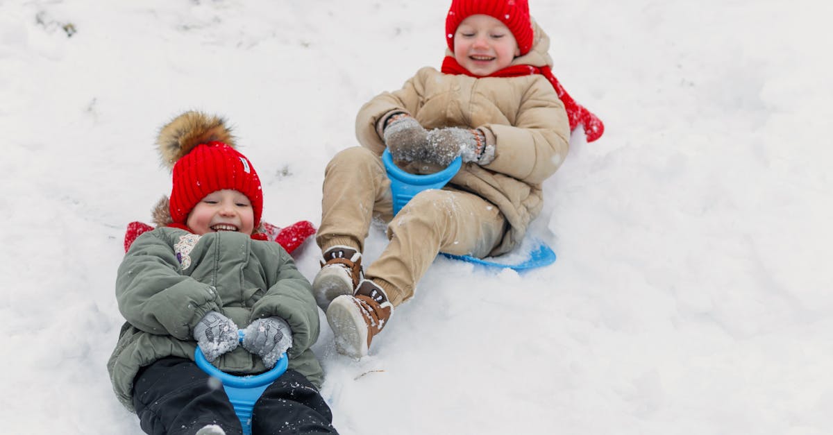 Joyful children sledding down a snowy hill, enjoying winter fun outdoors.
